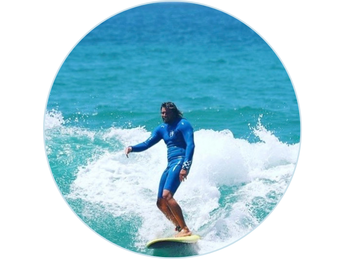 Ein grinsender Surfer mit blauem Wetsuit auf einem gelben Softboard, fährt genau auf die Kamera zu. Die Welle bricht sampft und entspannt. Das Bild macht einen sehr gechillten Eindruck vom Surfen.